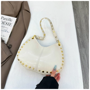 Detail view of cream crescent bag featuring gold stud trim and smooth leather texture
