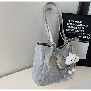Dettaglio borsa tote argento a pieghe con catena in metallo, perle e farfalla decorativa