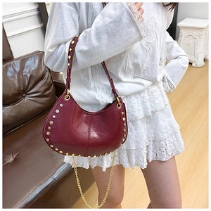 Lifestyle shot of wine red half-moon bag with gold studs and chain strap detail