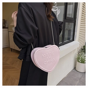 Detailed back view of model wearing pink heart shaped cross body bag with silver chain