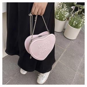 Detailed view of pink heart-shaped crossbody bag with embossed text and silver chain