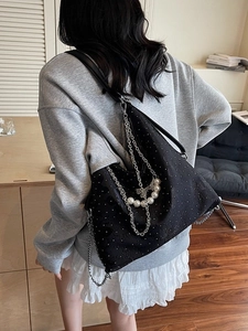 Retro black denim tote bag with silver metal chains and pearl accents on model back