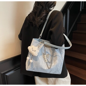 Dettaglio della borsa tote azzurra con texture stropicciata, catena e perle d'argento