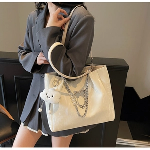 Dettaglio borsa shopper bianca con increspature, catene di perle e ciondolo peluche