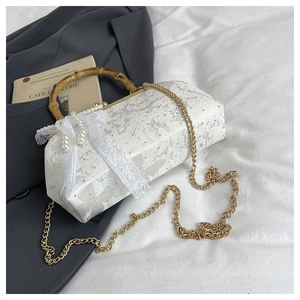 Macro detail of acrylic marble bag with bamboo handle, pearl charms, and lace bow