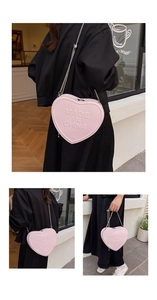 Macro shot of pink heart-shaped bag with embossed lettering and silver chain strap