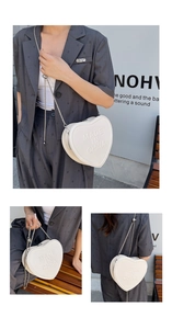 Macro detail of a white heart-shaped crossbody bag with embossed lettering and chain