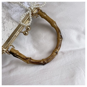 Detail of retro white lace evening bag with bamboo handle and pearl chain strap decoration