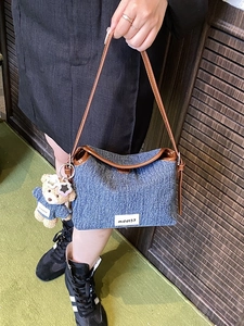 Blue denim crossbody bag with brown leather trim and a cute teddy bear charm
