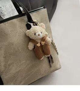 Detail of cute plush bear charm with corduroy overalls on a grey embossed tote bag