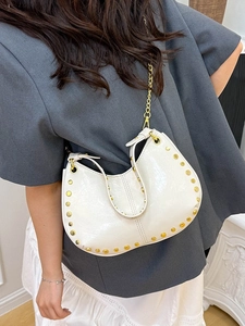 White crescent leather bag with gold studs and chain strap shown on a model