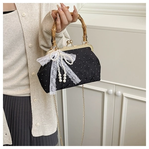 Detail of bamboo handle and pearl lace bow on black polka dot acrylic shell bag