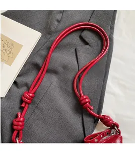 Detail of red leather shoulder bag with stylish knotted strap and metallic rivet hardware