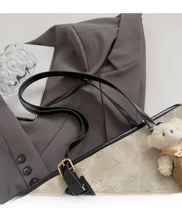 Detail of beige canvas tote with black leather strap and cute plush bear charm