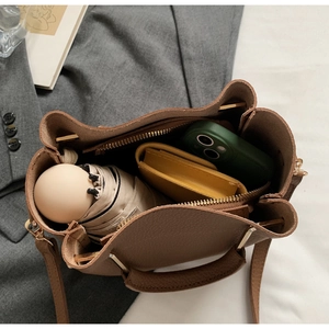 Interior detail of a brown leather handbag showing space for phone, wallet and umbrella