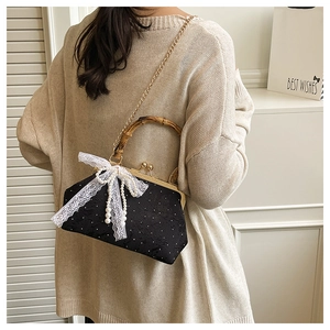 Detail of black jacquard handbag with bamboo handle, lace bow, and pearl charms