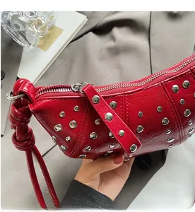 Detailed close-up of a red glossy leather handbag with silver stud rivets and a zipper
