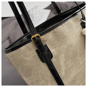 Detail of canvas tote bag with cartoon bear embossing and adjustable leather strap