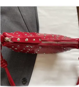 Close-up of a red leather bag with silver rivets and smooth metallic zipper detail