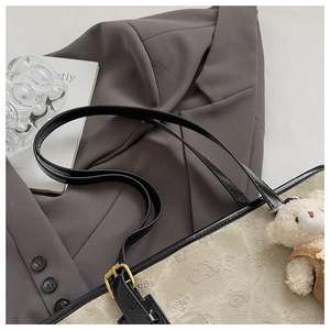 Close-up of beige canvas tote with cartoon bear patterns and black leather straps