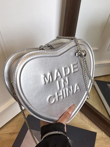 Silver heart-shaped mini crossbody bag with embossed lettering and metal chain strap