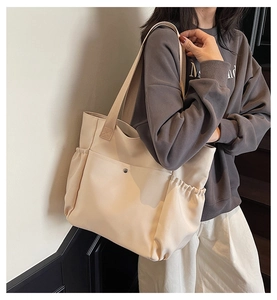 Close-up of beige nylon tote bag with functional front snap pocket and side elastic pockets