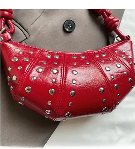 Macro detail of red crescent stud bag with silver rivets on sleek leather surface