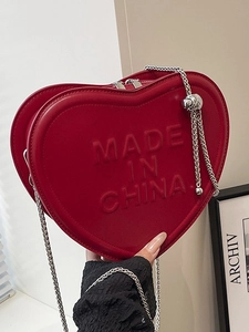 Red heart-shaped mini crossbody bag with embossed lettering and silver metal chain strap