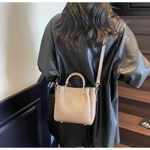 Detail of apricot pebbled leather tote featuring gold hardware and adjustable strap