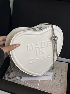 Cream heart-shaped crossbody bag with embossed lettering and silver chain strap
