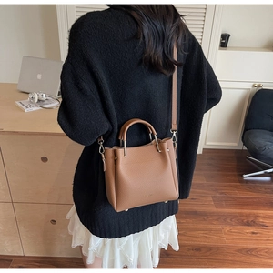 Detailed texture of brown pebble leather bucket bag with gold hardware and logo