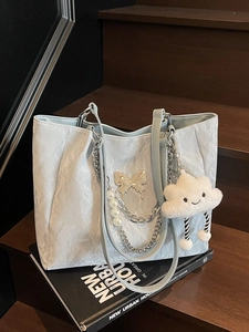 Borsa tote a pieghe azzurra con farfalla d'argento e catena di perle su libro