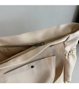 Detail shot of smooth metal zipper closure and canvas texture on beige shoulder tote bag