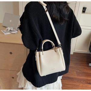 Detail of cream white lychee texture handbag with elegant gold hardware and ZHONMA logo