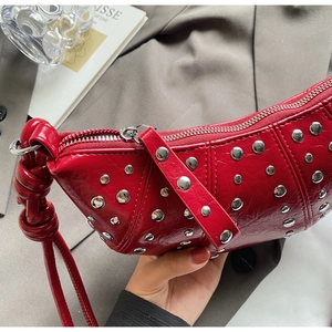 Close-up of red wrinkled patent leather with silver rivets on a chic shoulder bag