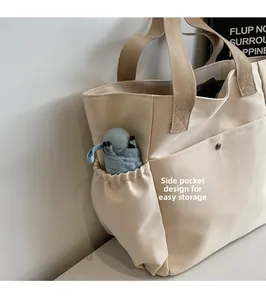 Detail of canvas tote side pocket with umbrella and front pocket with metal snap button