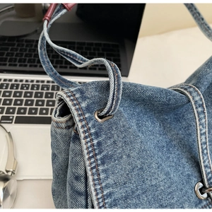 Vue détaillée du sac en denim délavé avec surpiqûres orange et œillets métalliques