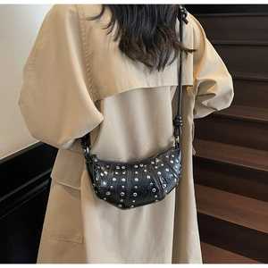 Detail of black crescent crossbody bag with silver studs and knotted shoulder strap