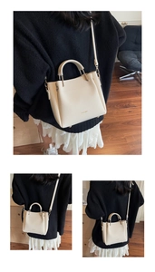 Detail of cream lychee leather handbag featuring a unique gold metal semicircular handle