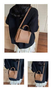 Detail of brown litchi pattern leather tote bag with gold metal logo and handle accents