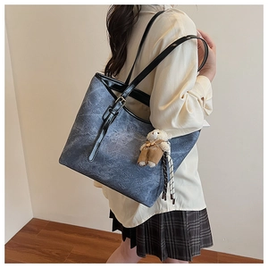Detail of dark blue vintage tote bag with light floral pattern and bear pendant detail