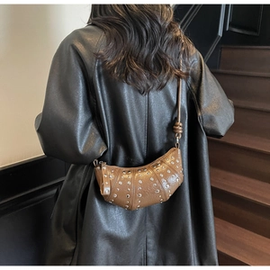Detail view of brown crescent dumpling bag with silver studs and cracked leather texture