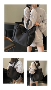 Detail of a large black nylon tote bag with side pockets and a durable metal snap closure