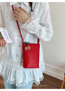 Detail of red textured leather tote with cherry charm on white lace shirt outfit