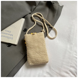 Détail du petit sac bandoulière en maille crème avec fermeture à bouton et fleur brodée