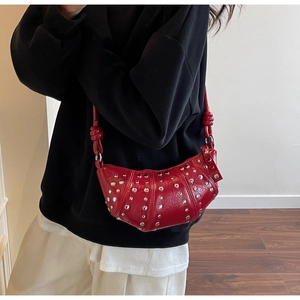 Detail view of red crescent bag with shiny pleated leather and silver rivet studs