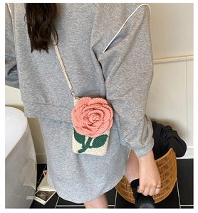Détail du sac bandoulière tricoté main avec rose 3D et feuilles vertes sur coton blanc