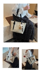 Close-up of beige embossed tote bag featuring vintage floral patterns and cute bear charm