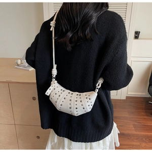 Detail of white dumpling crossbody bag with metal rivets and stylish knotted strap