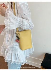 Detail of yellow lychee leather bucket bag with cherry charm and brand logo